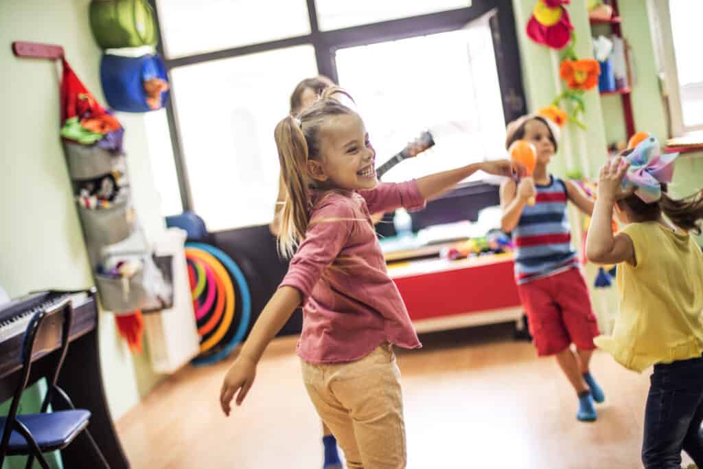 Young children dancing an making music in preschool