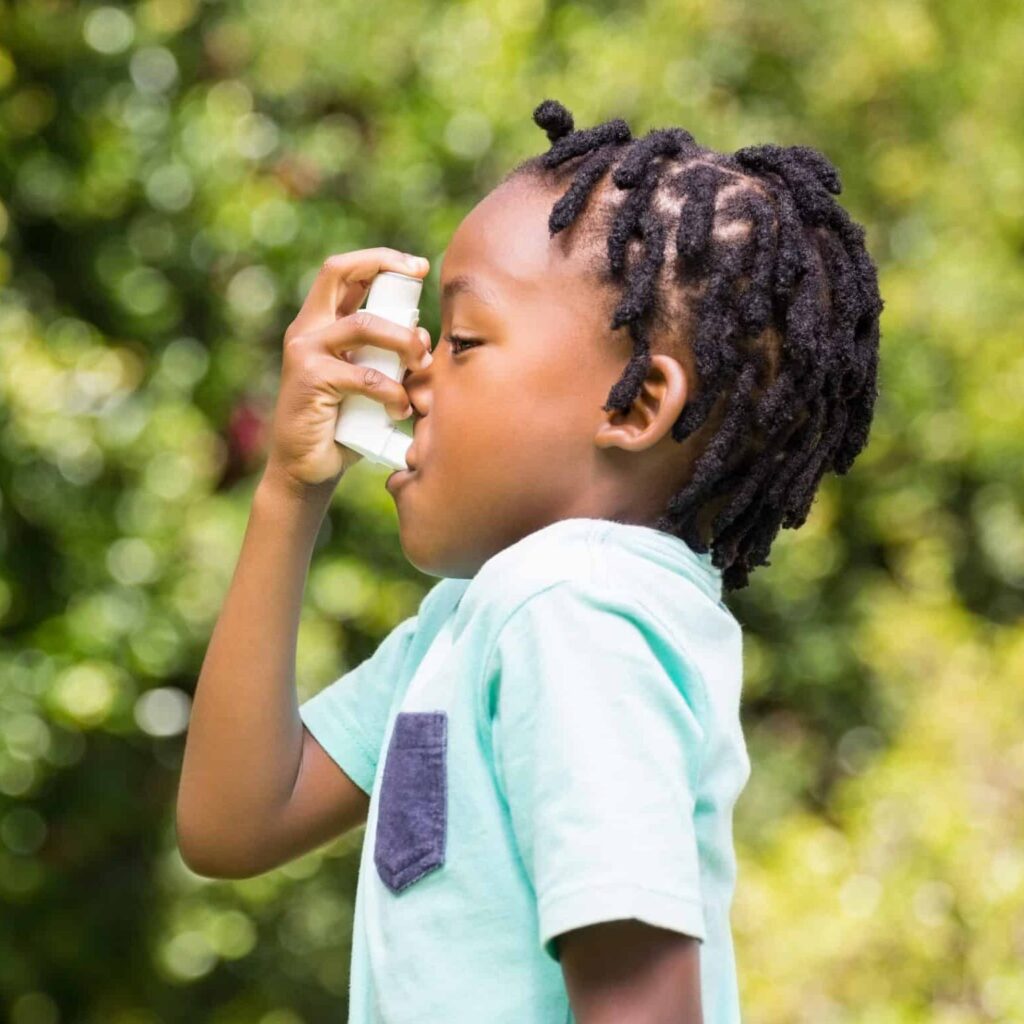 Boy using an asthma inhaler in the park