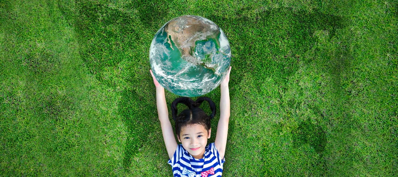 photo of child laying on grass holding a ball that represents Earth