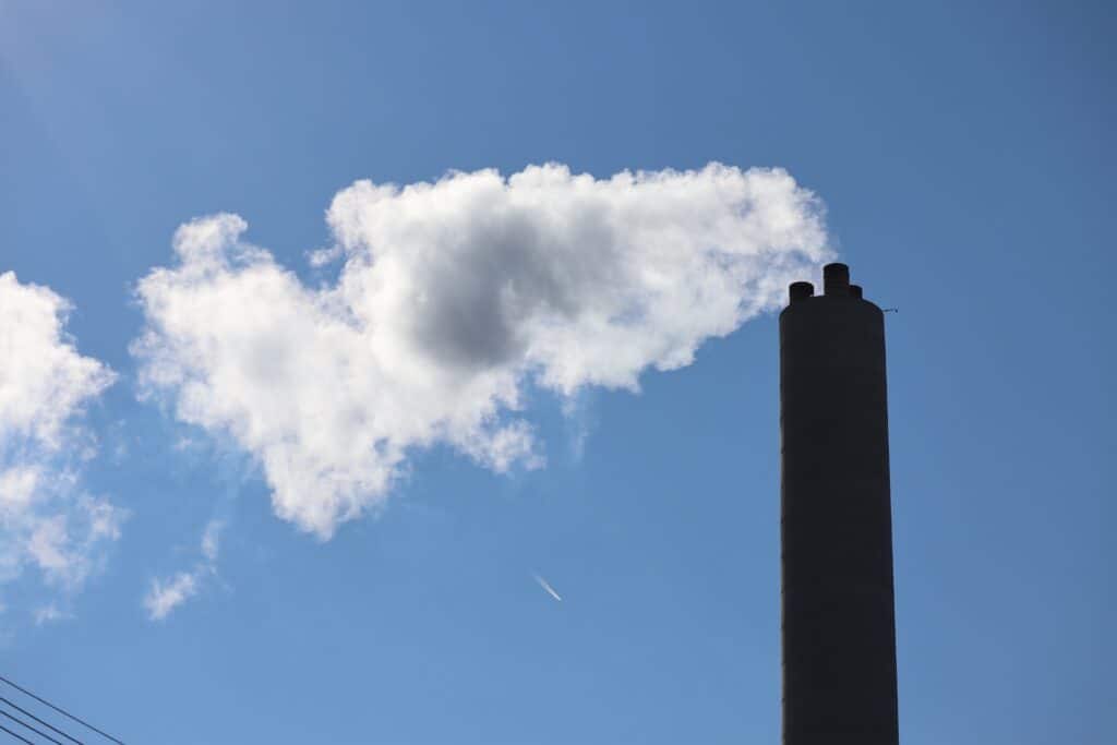 Image of a factory stack polluting on a sunny blue sky