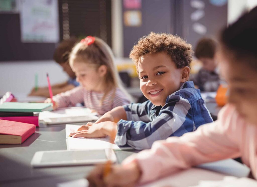 Smiling boy in class learning with others