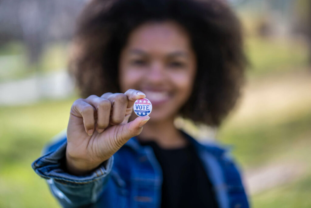 Woman, out of focus, holding vote button, in focus