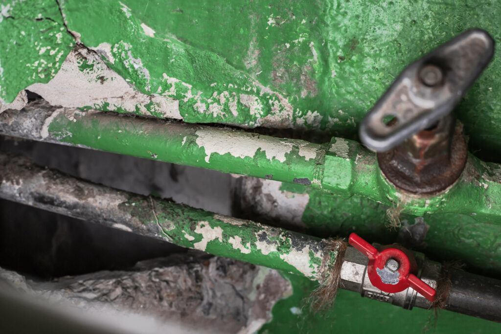 Old plumbing, showing pipes and valves covered in flaking, green paint