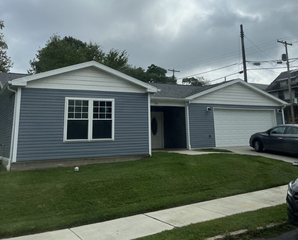 Blue house with garage and car parked in the driveway.