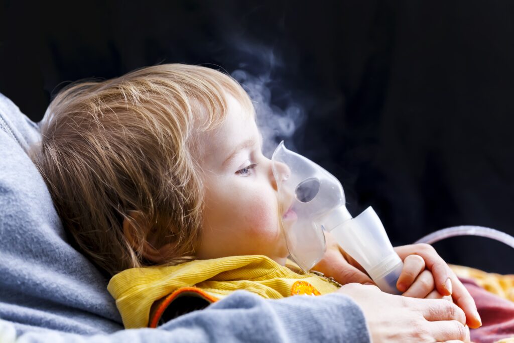 A person hold a child with asthma with a mask on their face