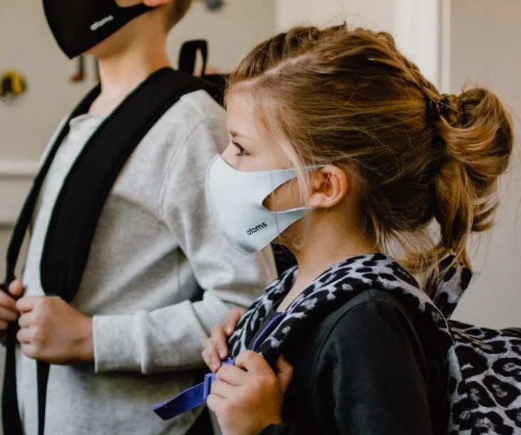photo of children wearing face masks and back packs