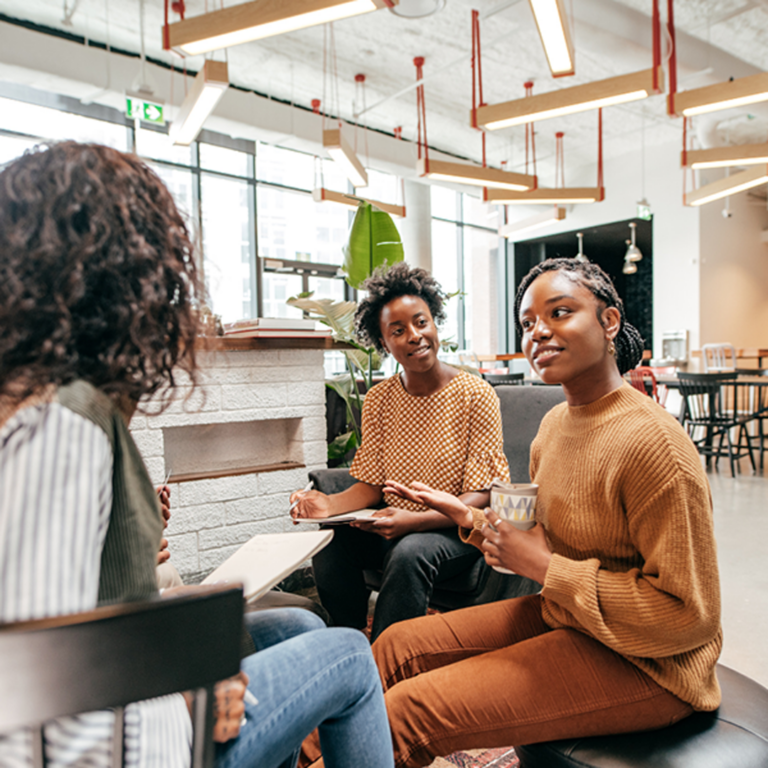 Group of three women having a discussion in an industrial looking office space