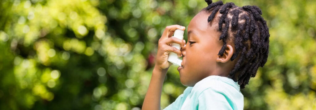 Young boy using inhaler outside